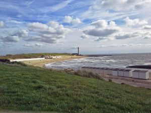 Meer und Deich in Westkapelle mit Strandhäuschen und neuem Leuchtturm im Hintergrund