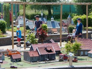 Eltern mit zwei kleinen Kindern gehen durch Mini Mundi Freizeitpark Middelburg