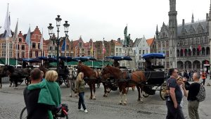 Marktplatz von Brügge mit Touristen und Pferdedroschken
